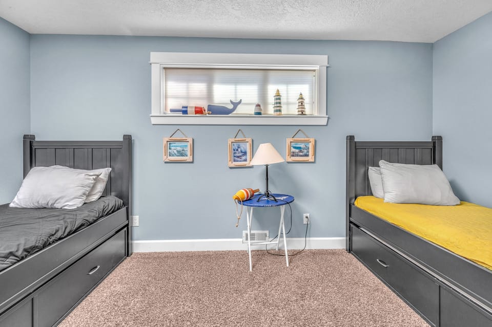 Your kids will love this nautical-themed room with twin beds and playful coastal decor creating the perfect seaside adventure.