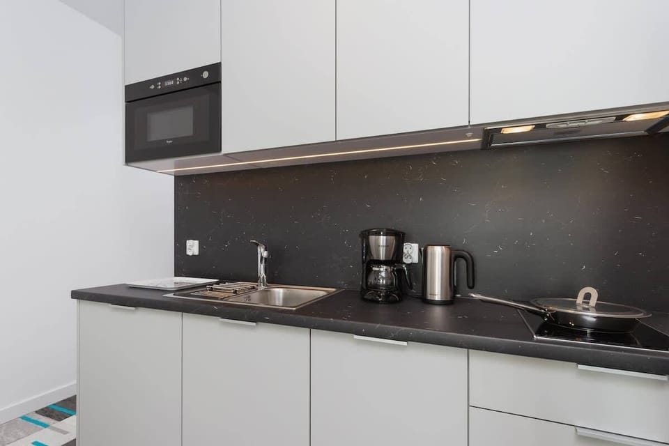 A second kitchenette view, showing additional countertop space, a microwave, and a sink. The cabinets are white, giving the area a bright look.