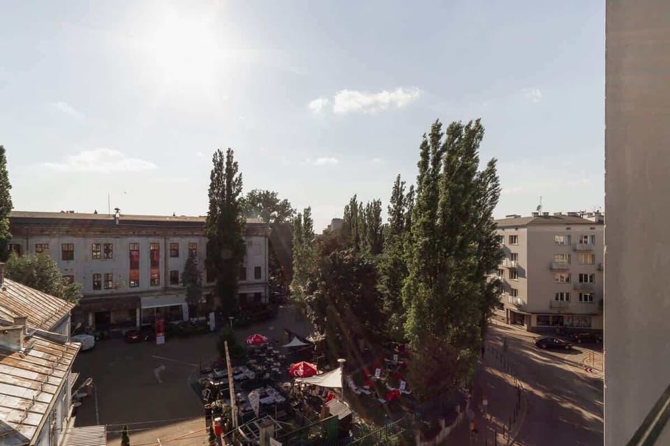 A view from a balcony overlooking a residential area and some greenery. The scene captures an open space with a peaceful atmosphere.