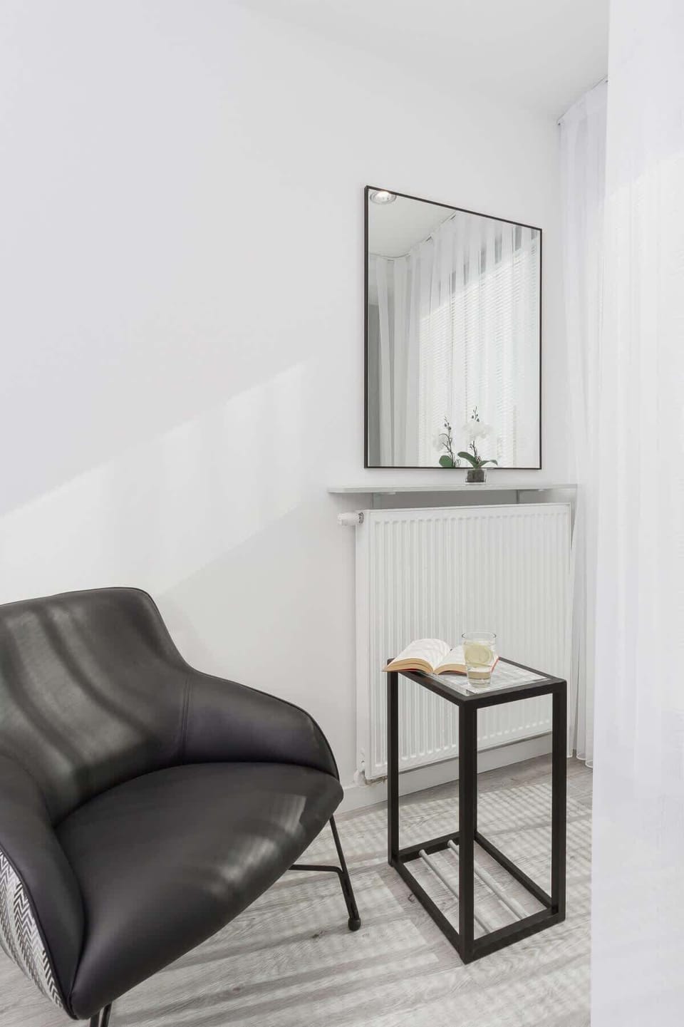 A sleek black armchair paired with a small, minimalist table. The setup creates a stylish corner for relaxing or enjoying a drink.