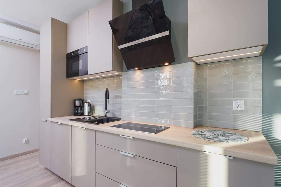 A compact kitchen area with sleek cabinetry, a stove, and a range hood. The design is modern with white and wood finishes.