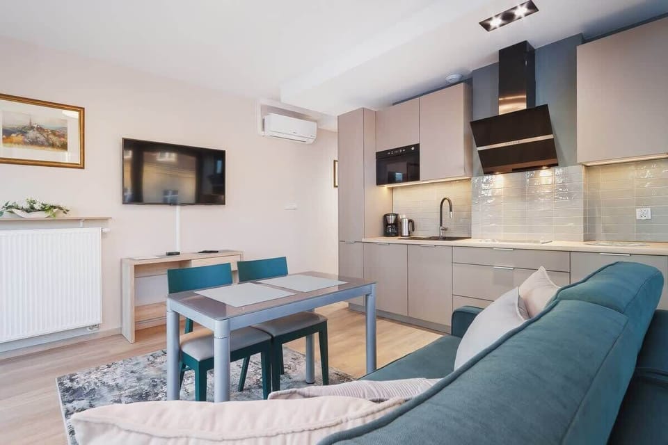 A stylish open-plan kitchenette featuring a built-in oven, ample countertop space, and a bright, minimalist design. It seamlessly connects to the dining area.