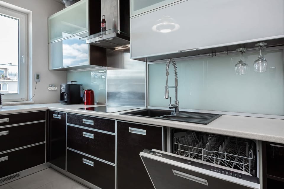 A contemporary kitchen with high-gloss black cabinetry, stainless steel appliances, and a sleek countertop, offering a streamlined, modern look.