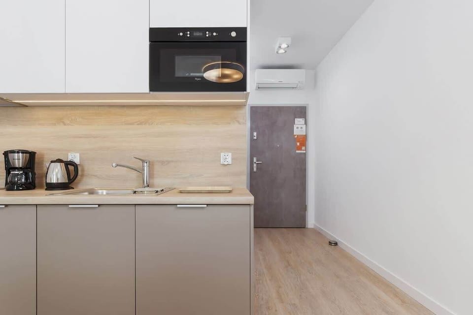 A sleek kitchenette with white cabinets, a black countertop, and essential appliances. It’s compact yet fully equipped, perfect for small meals and quick snacks.