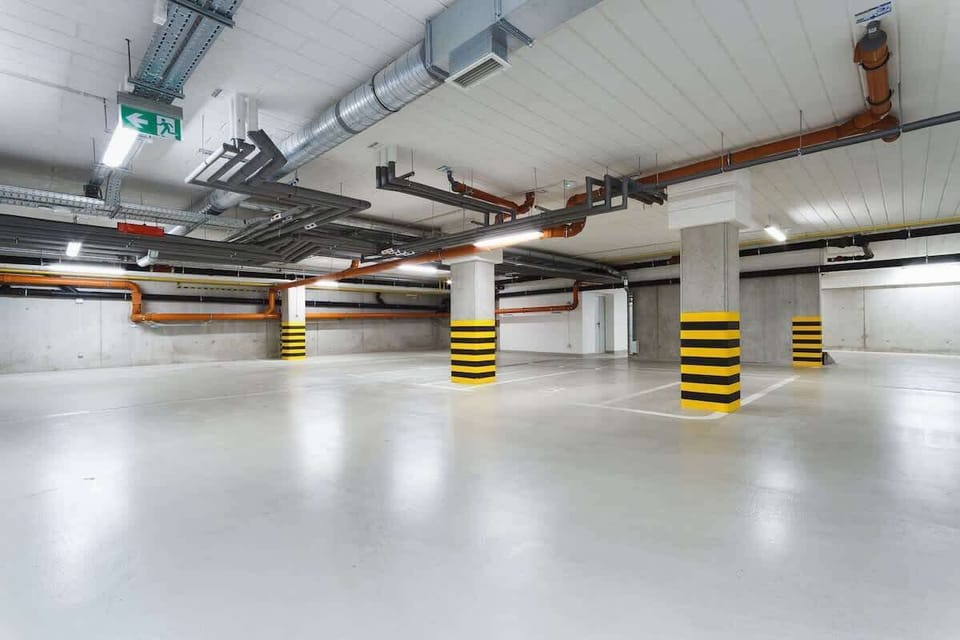 A view of an underground parking area, featuring concrete floors and yellow safety markings on the pillars. The space is well-lit and organized.