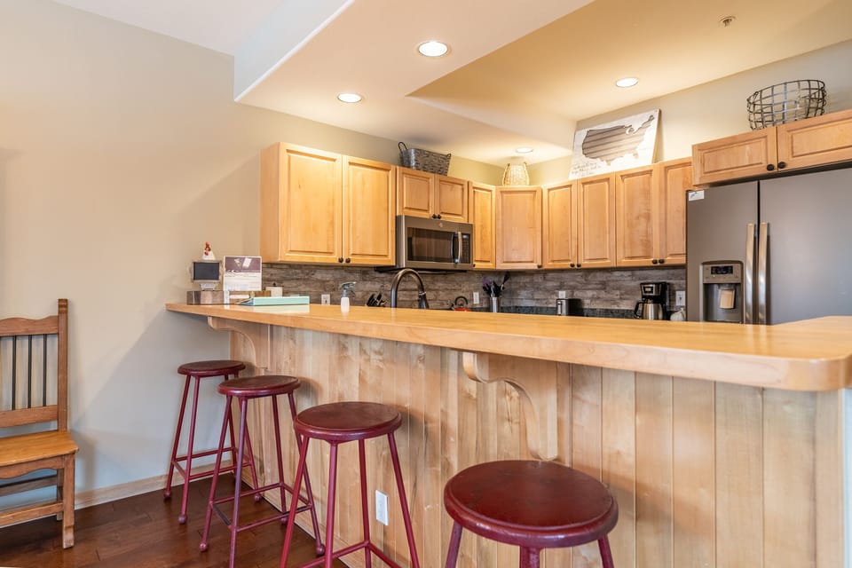 Your spacious kitchen features warm wood cabinets, granite counters, and a breakfast bar perfect for morning coffee or casual meals.