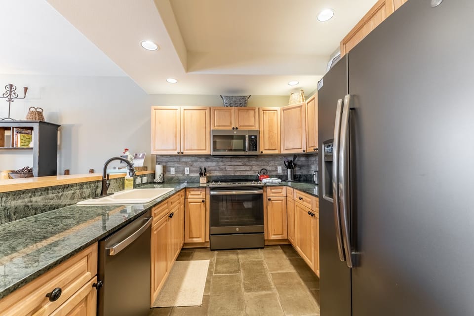 Your fully equipped kitchen features granite countertops, stainless steel appliances, and warm wood cabinets for memorable meal preparation.