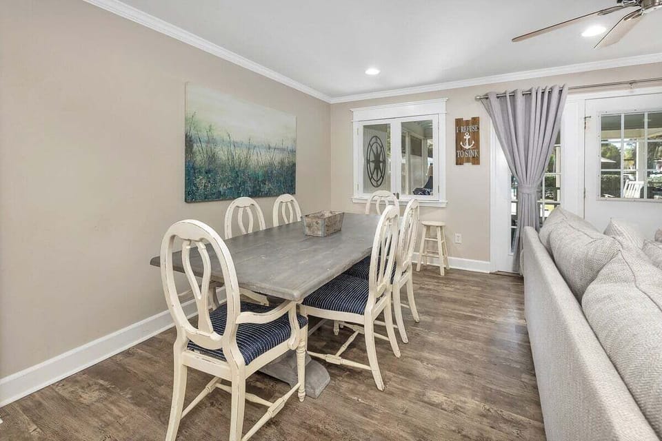 Dining area with white chairs, wood table, patio doors
