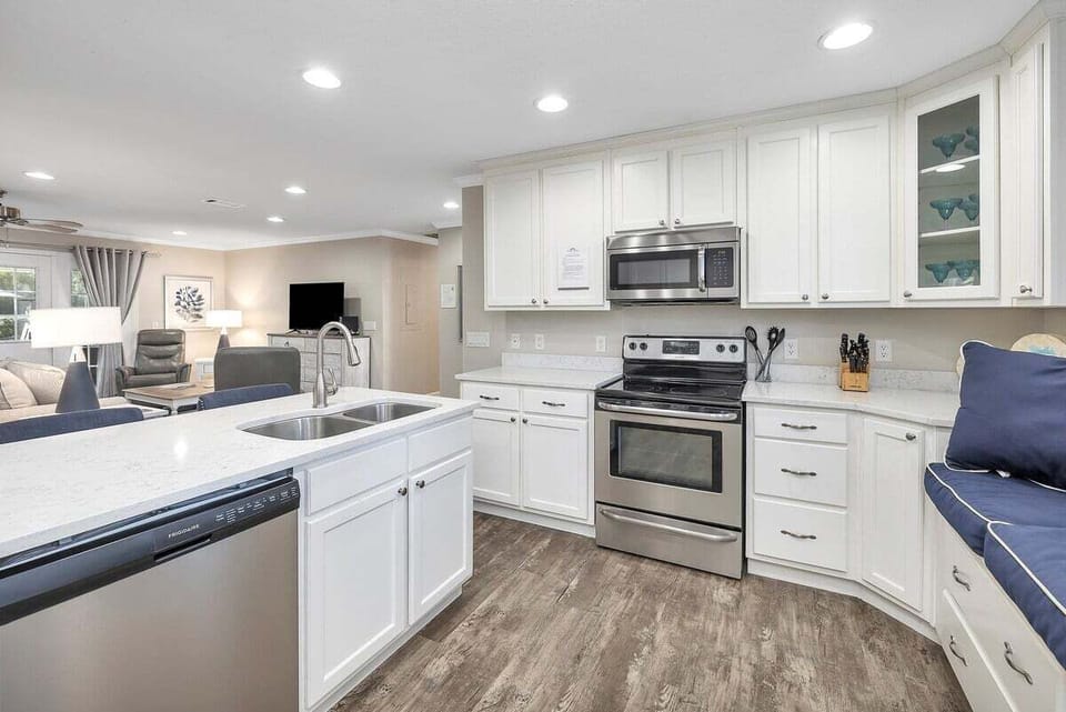 White kitchen with stainless range, microwave, and sink