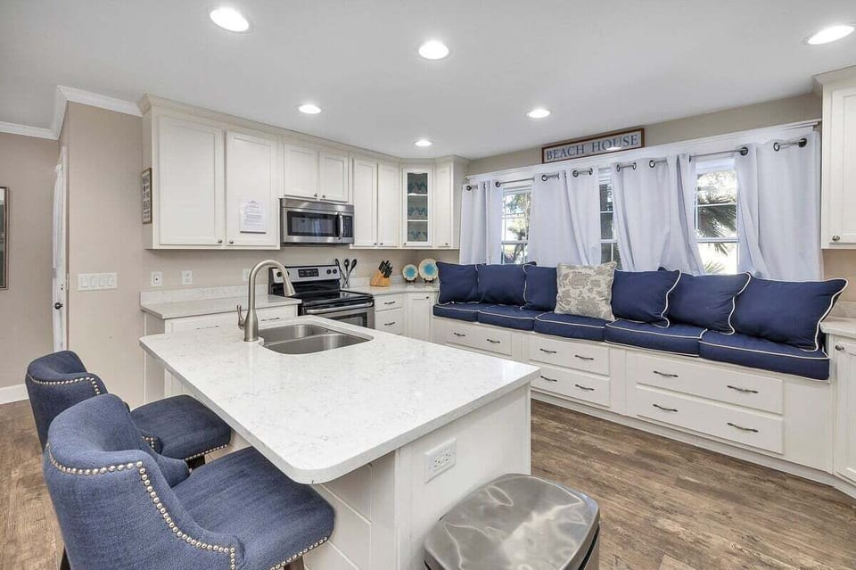 White kitchen island with navy bar stools, stainless steel appliances