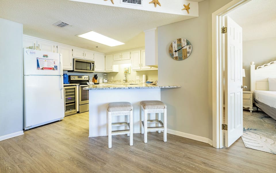 This modern kitchen features white cabinetry, granite countertops, and a breakfast bar, perfect for preparing meals