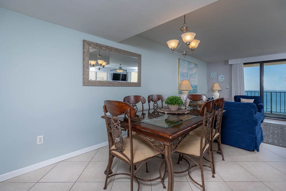 Inviting dining area features elegant wooden furniture and a stunning view of the sparkling waters beyond