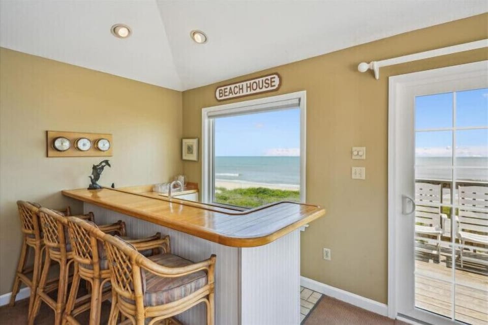 Your breakfast bar overlooks endless ocean views through this beach house window, where mornings begin with sea breezes and the rhythmic sound of waves rolling ashore.