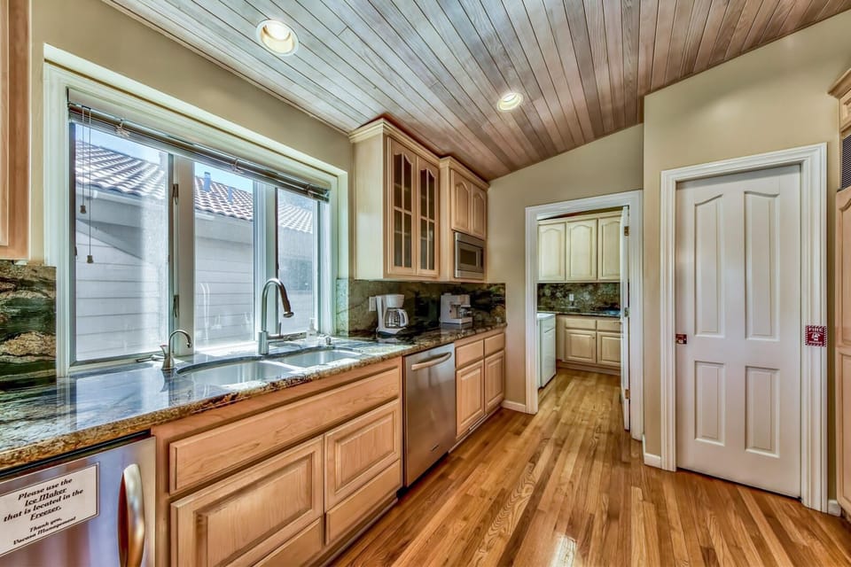 Your gourmet kitchen awaits with granite counters, stainless appliances, and warm wood details under a stunning plank ceiling.