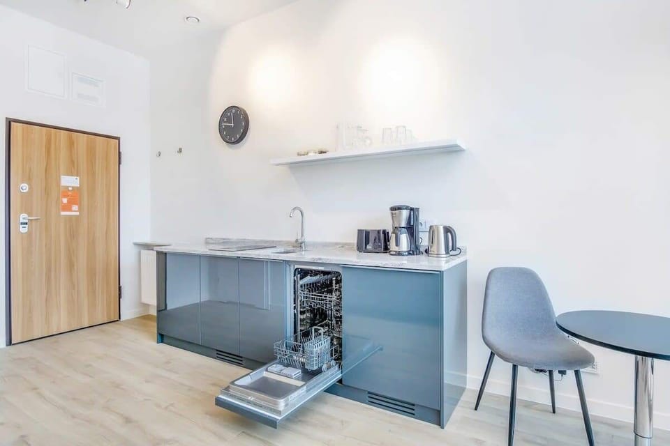 A compact kitchenette featuring a dining table, coffee maker, and sleek countertops, ideal for quick meals and refreshments.