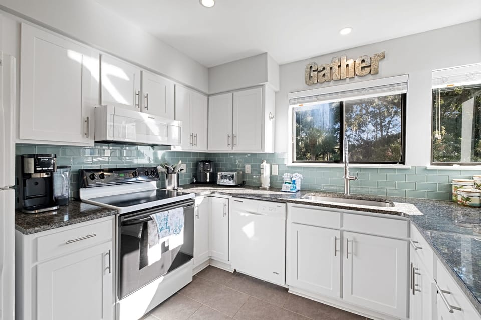 Spacious & sunny: White shaker cabinets, sea-glass backsplash, and that perfect ‘Gather’ sign set the vibe for relaxed meals and morning coffee at our Hilton Head villa.