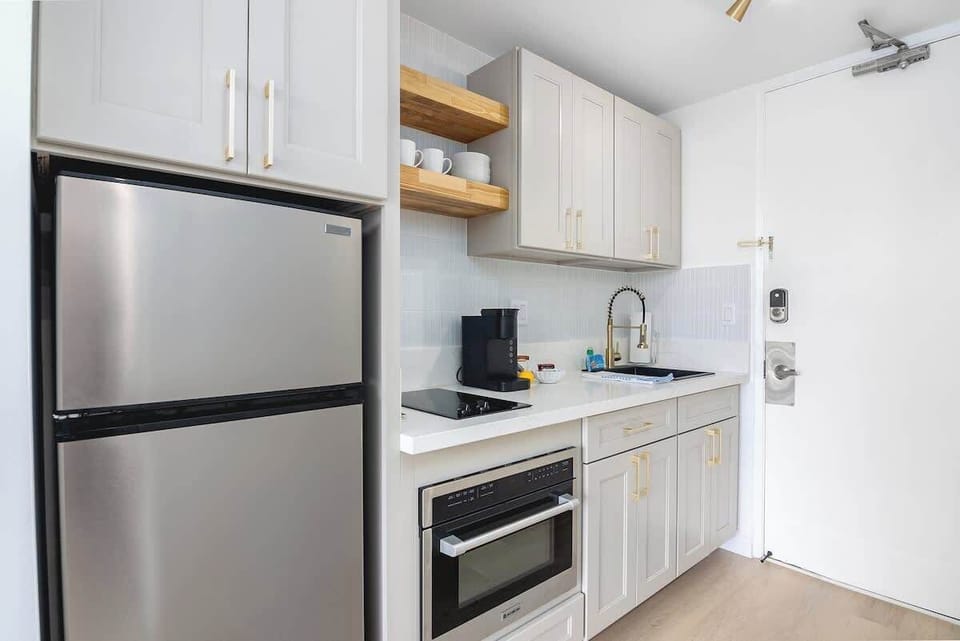 A newly renovated kitchenette with a full-size refrigerator, a 2-burner stove, and a new Keurig coffee maker.