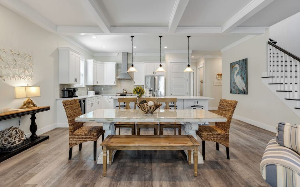 Gather around your elegant dining table in this open-concept space where coastal charm meets modern comfort for memorable meals.