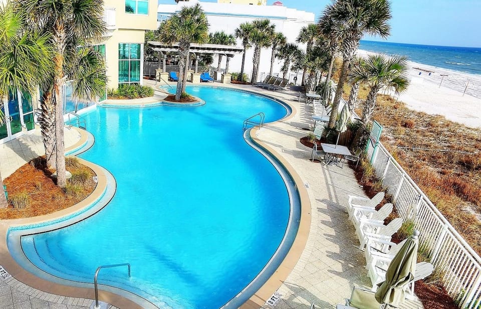 The outdoor pool is just steps from the sandy beach, offering direct access to both crystal-clear water and oceanfront relaxation under swaying palms.