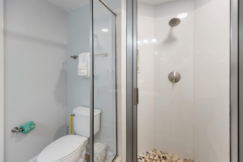 Step into your sleek glass-enclosed shower with rainfall head, where modern fixtures and pristine white walls create your perfect retreat.