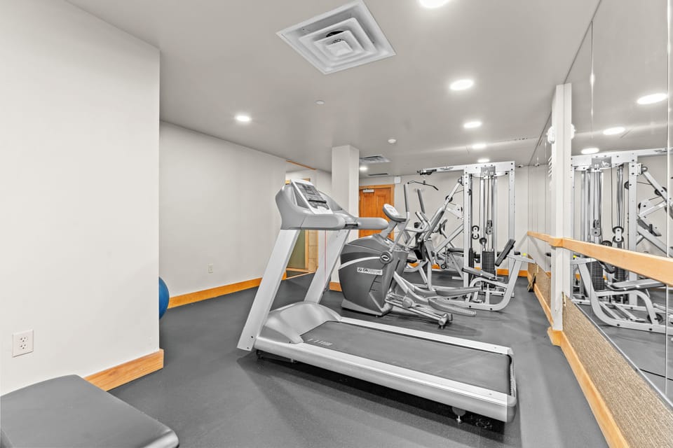 Stay on track with your fitness routine in this well-equipped workout space featuring cardio machines and strength training equipment.