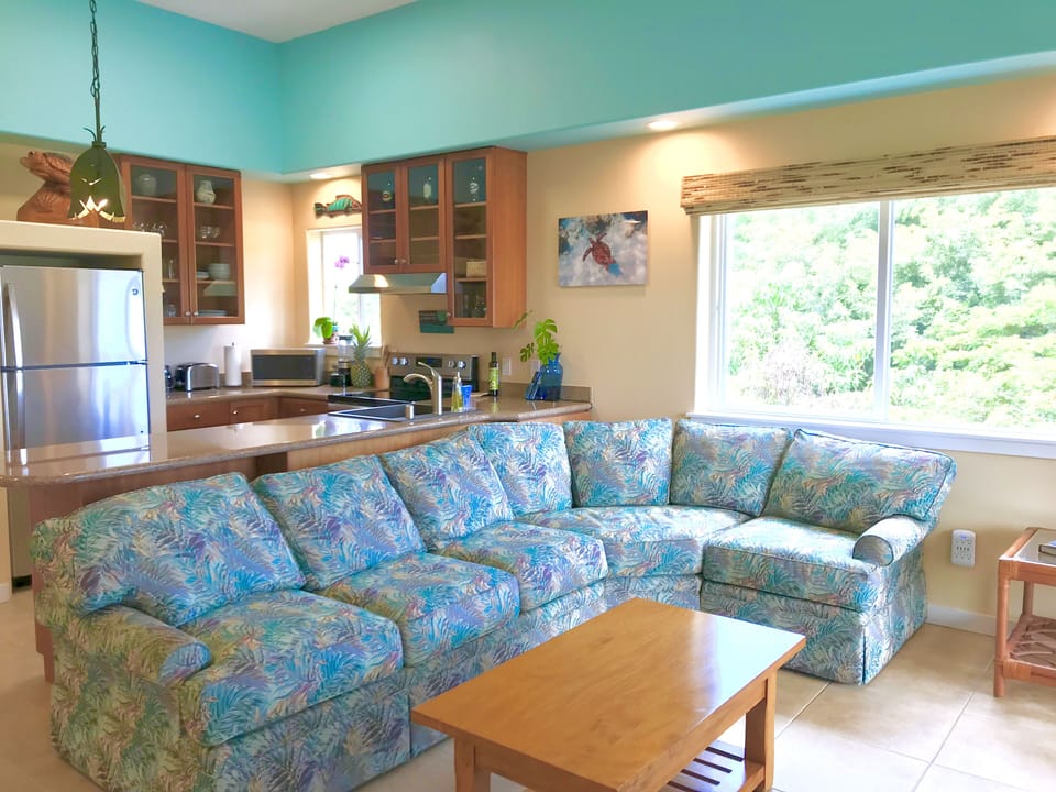 Open concept great room with high ceilings and treetop and ocean views.