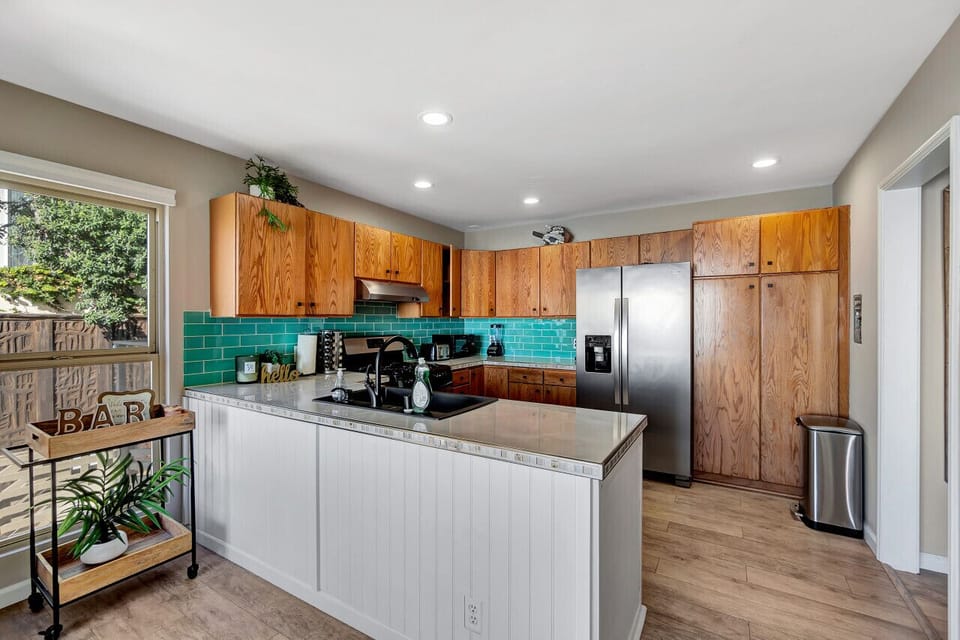 Open kitchen w/ turquoise tile backsplash & generous counter space.
