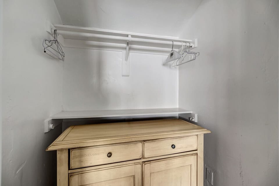 Compact closet space w/ dresser & hanging rack for easy storage.