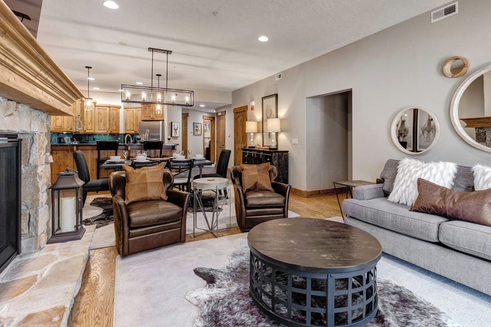 Relax in your elegantly appointed living space featuring leather armchairs, a cozy fireplace, and seamless flow to your fully equipped kitchen