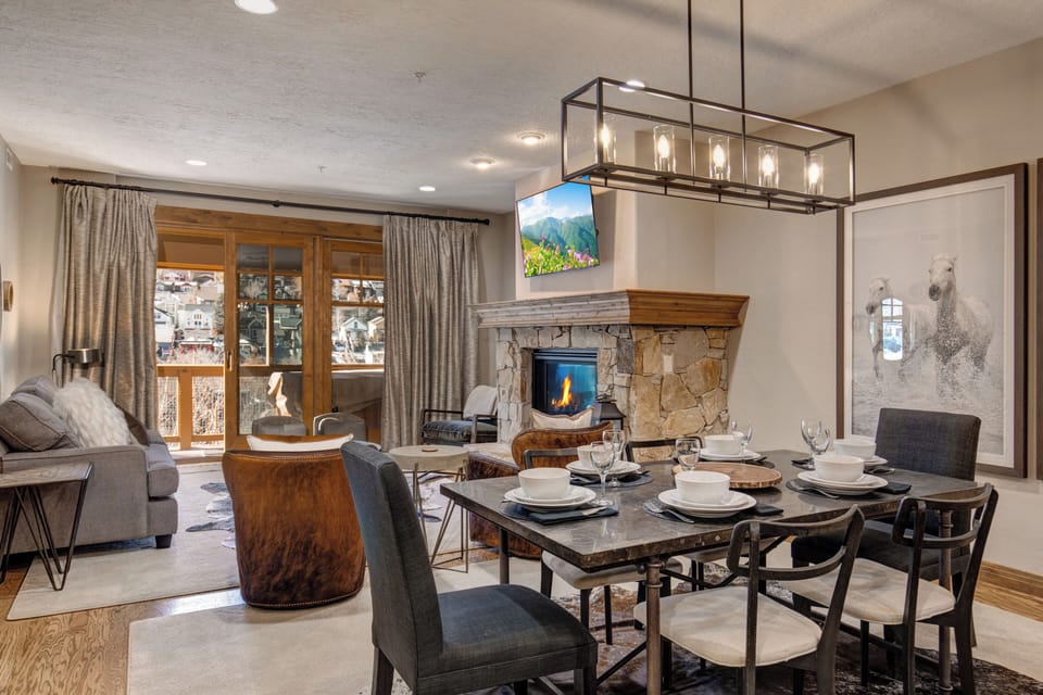 Gather around your elegant dining table while enjoying the warmth of your stone fireplace and mountain views through floor-to-ceiling windows.