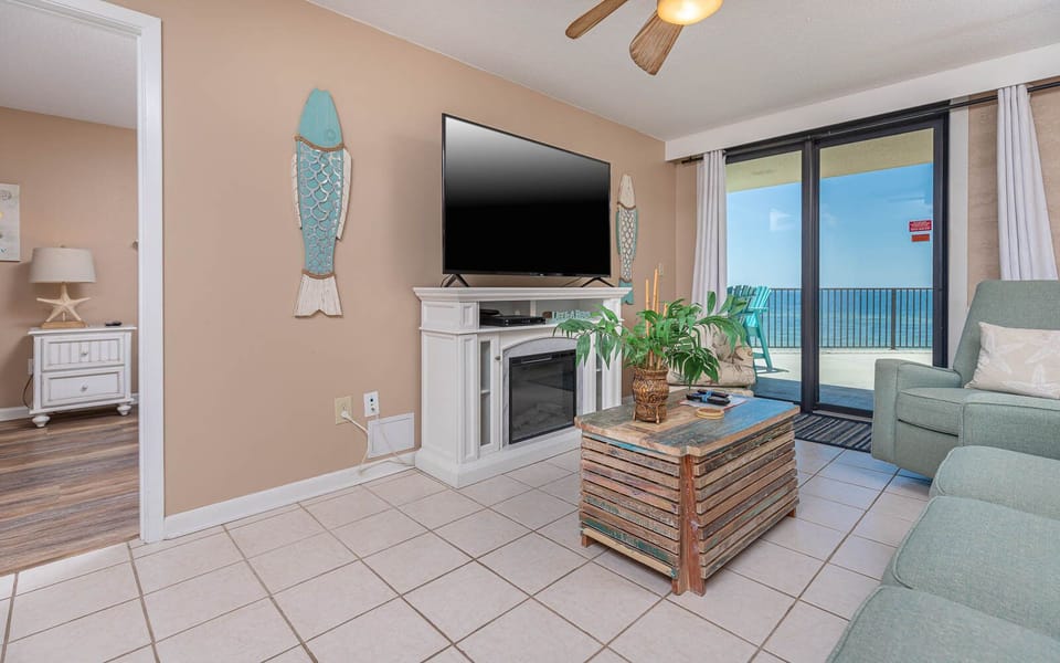 This inviting living area features a large TV, cozy seating, queen sofa-sleeper, and a breathtaking view from the balcony