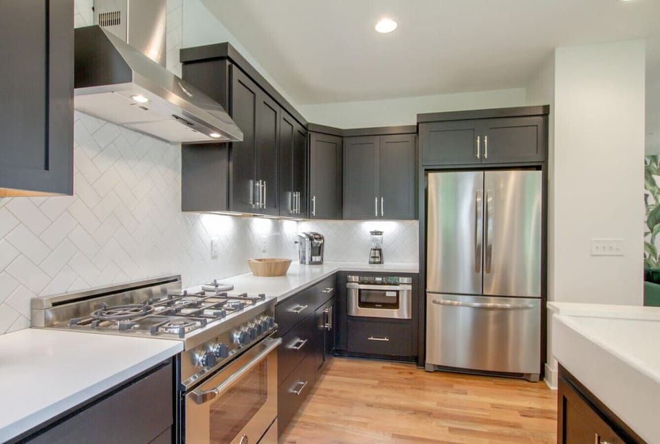 Kitchen close-up with dark cabinets, professional gas range with hood, and stainless steel refrigerator
