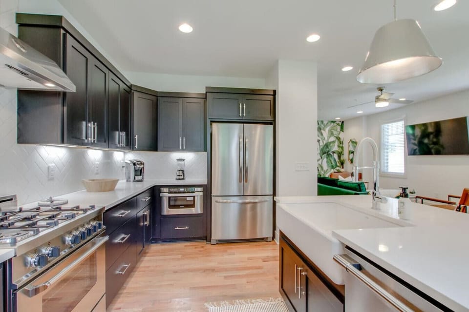 Spacious kitchen with dark cabinets, stainless steel refrigerator, and white countertop island