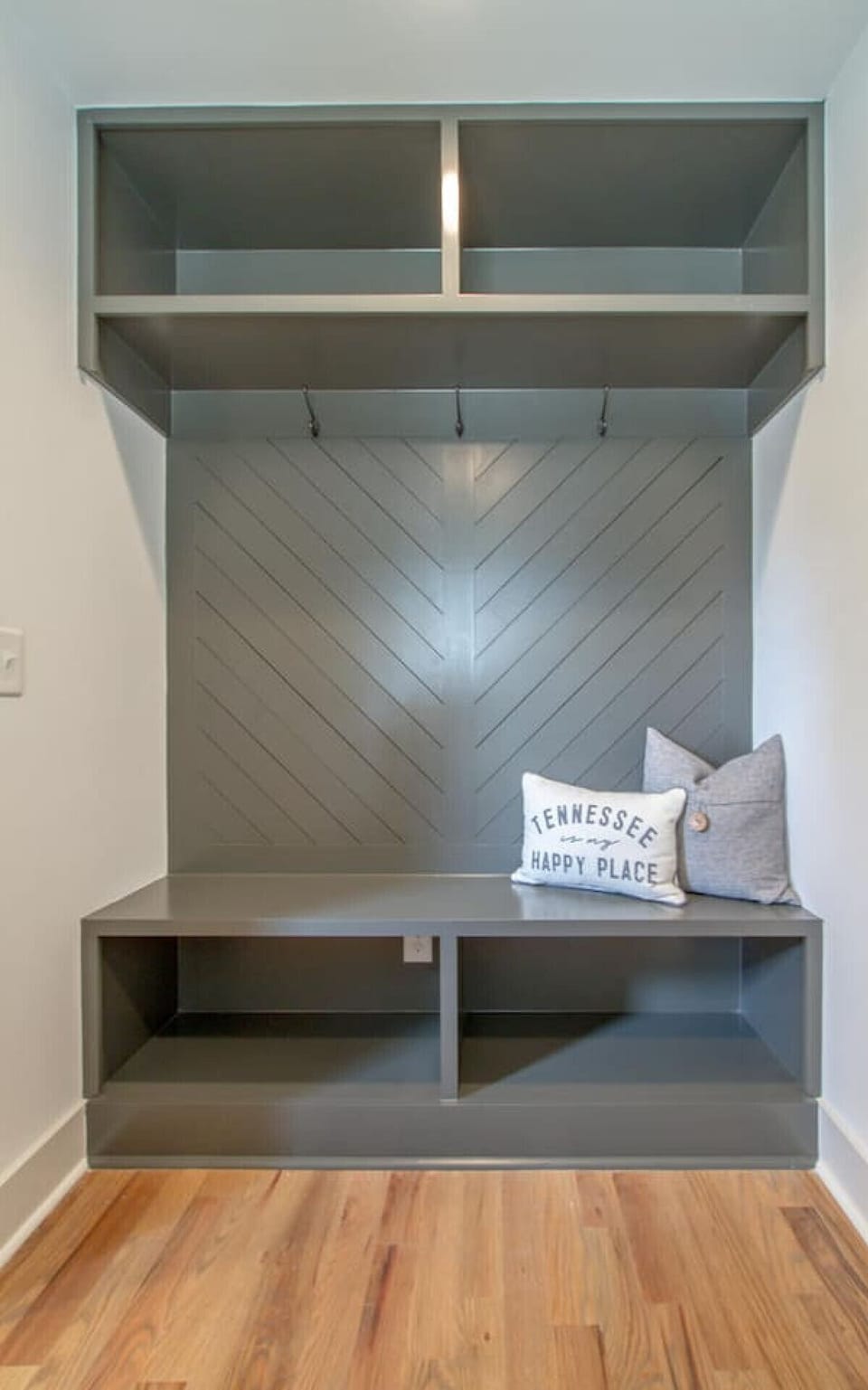 Mudroom with a herringbone wood accent wall and bench with decorative pillows