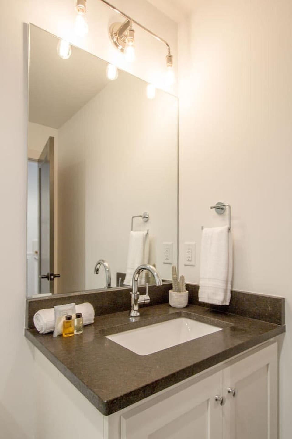 Bathroom vanity with sink, mirror, and folded towels