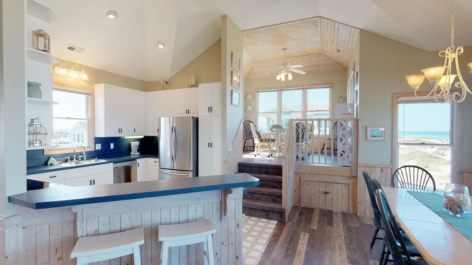 Kitchen to the left, dining to the right, game table and seating beyond up the half flight.