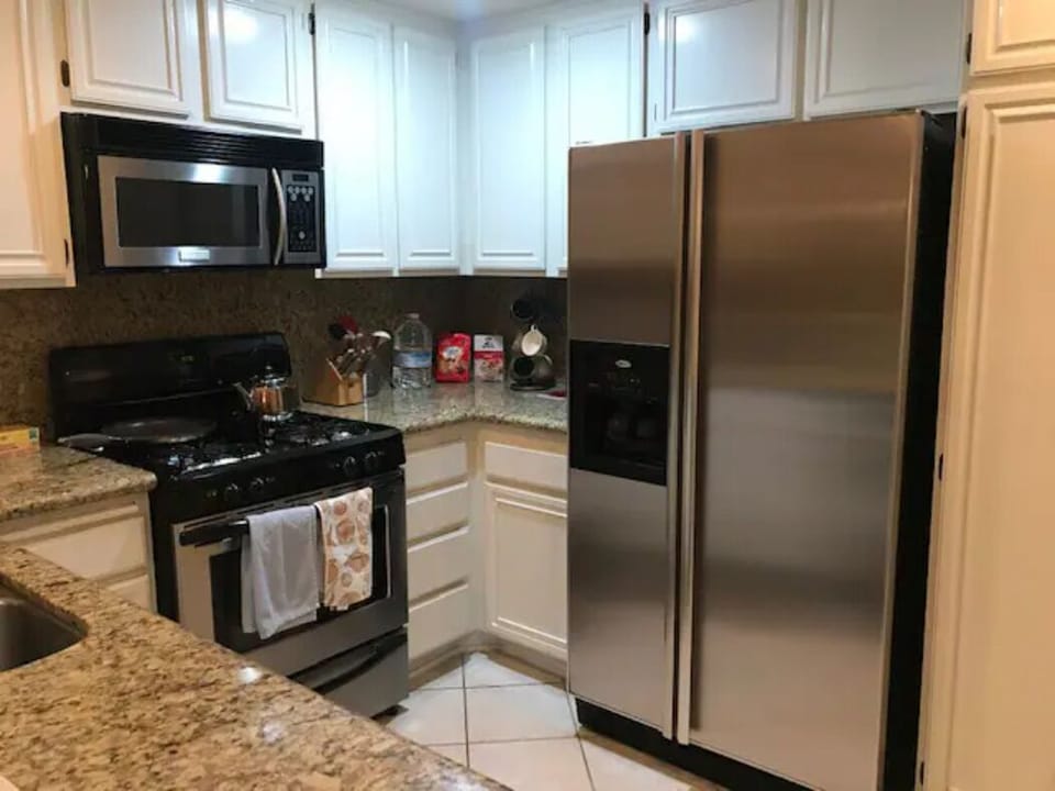 Kitchen view of stove, microwave, refrigerator.
