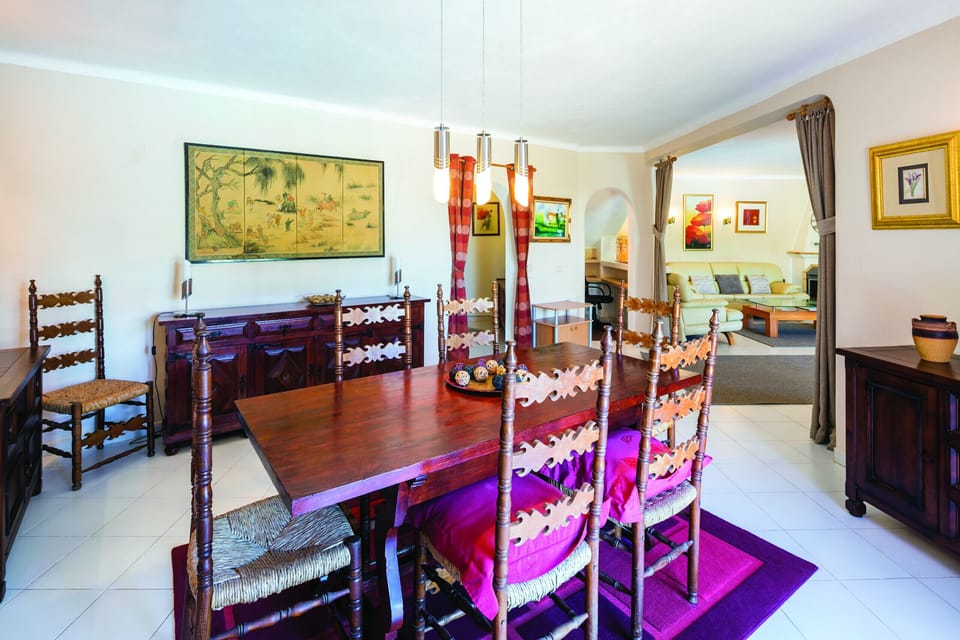 Traditional dining room with wooden table, carved chairs, and colourful Portuguese decor at Casa Santalena villa in Carvoeiro, Algarve
