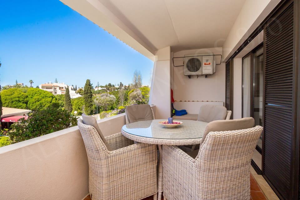 Sunny balcony terrace at Alporchinhos 840 holiday apartment with wicker furniture and panoramic views of the resort gardens and Algarve coastline under blue skies