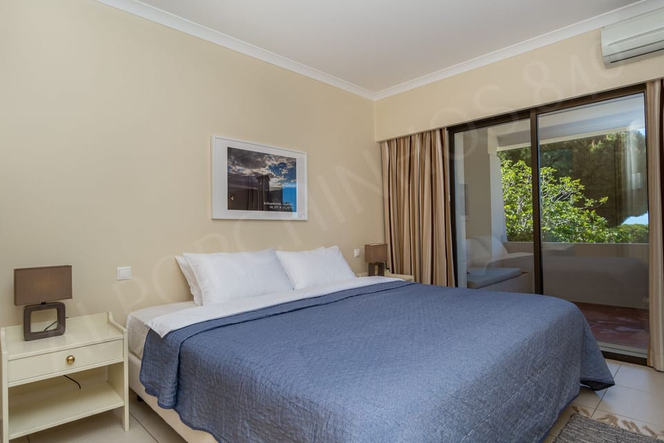 Cosy second bedroom in Alporchinhos 840 holiday apartment with double bed, bedside table, and coastal artwork creating a relaxing retreat in the Algarve