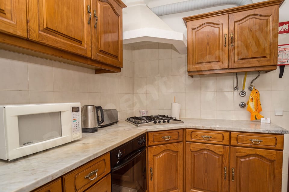 Fully equipped kitchen at Apartment Amalia in central Carvoeiro, with traditional wooden cabinetry, gas hob, microwave, toaster, kettle, and tiled countertops providing all essentials for self-catering holidays