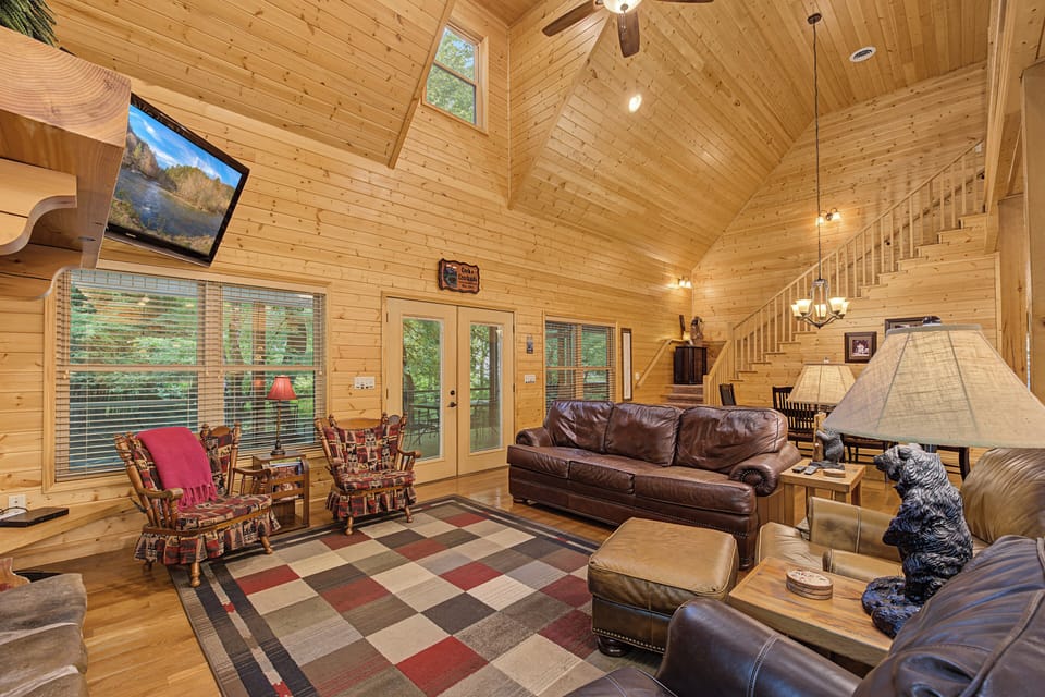 Sink into plush leather sofas beneath soaring vaulted ceilings, where warm wood tones and natural light create your perfect mountain retreat sanctuary.