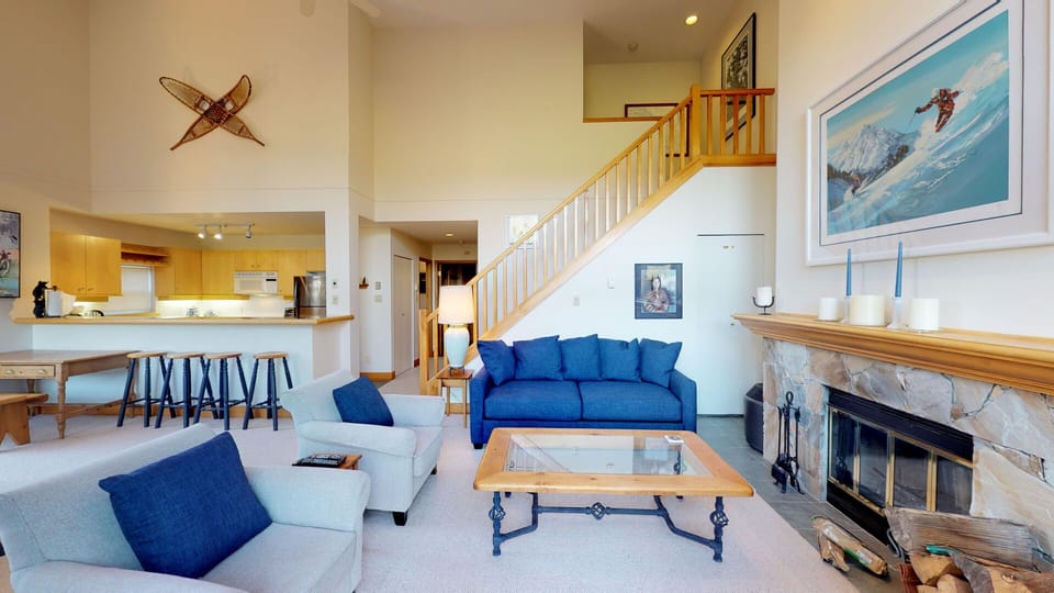 The living room features vaulted ceilings, a wood-burning fireplace, and stunning views.