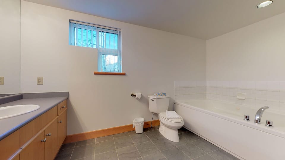 The ensuite features a soaker tub, double vanity, and serene natural tones.