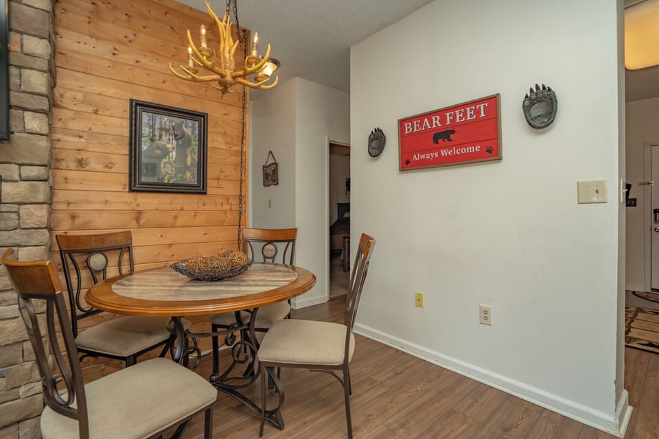 Gather around the rustic dining table under the warm glow of an antler chandelier, where charming bear-themed touches and natural wood accents make every meal feel like a mountain retreat.