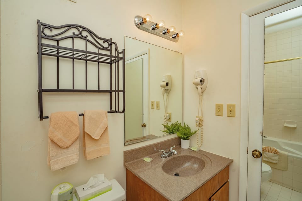 Freshen up in your private bathroom with soft towels, a vanity mirror, and thoughtful touches like greenery and a hairdryer for your convenience.