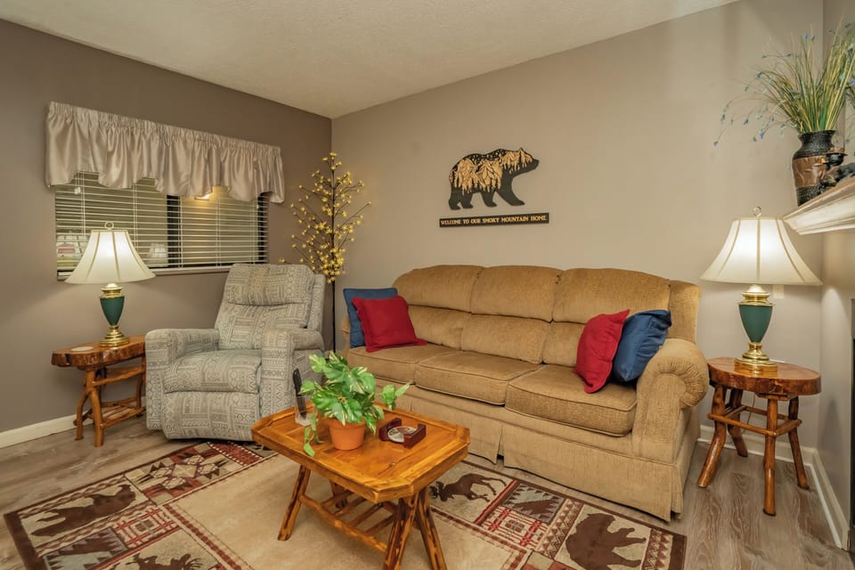 Cozy living room with rustic mountain charm, warm lighting, and comfortable seating. Handcrafted wood furniture and nature-inspired touches create the perfect retreat.