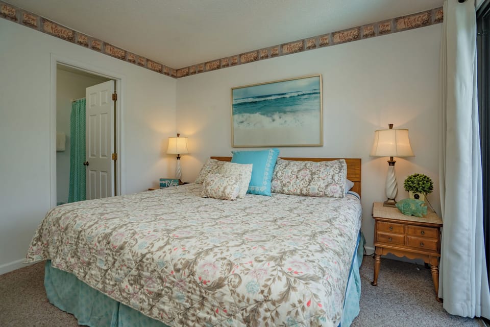 Sink into a plush bed dressed in soft, coastal-inspired linens. Warm lamps flanking each side create a cozy glow while you unwind in your serene retreat.