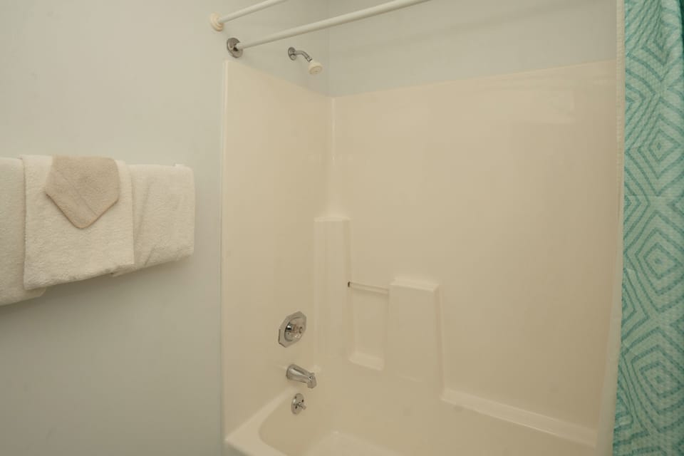 Your private bathroom features a spotless tub-shower combo with fresh towels and a modern showerhead—perfect for unwinding after a day of exploring.