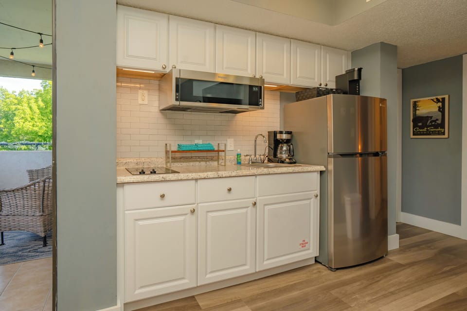 Your kitchenette features bright white cabinetry, granite counters, and stainless appliances—including a full fridge, microwave, and coffeemaker—perfect for light meal prep during your stay.